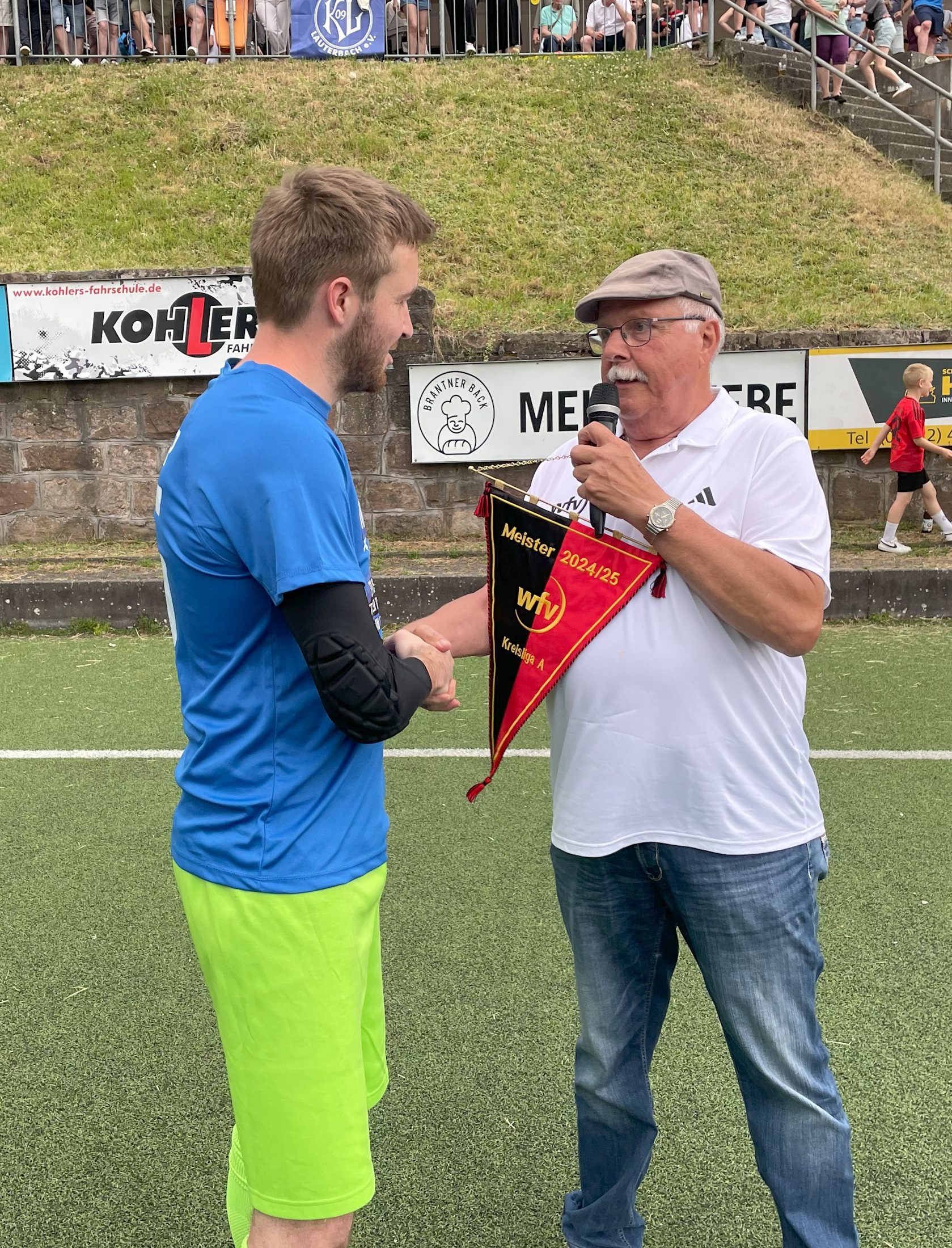 Staffelleiter Reiner Merz eberreicht Spielfhrer Jonas Moosmann den Meisterwimpel Saison 2024/2025